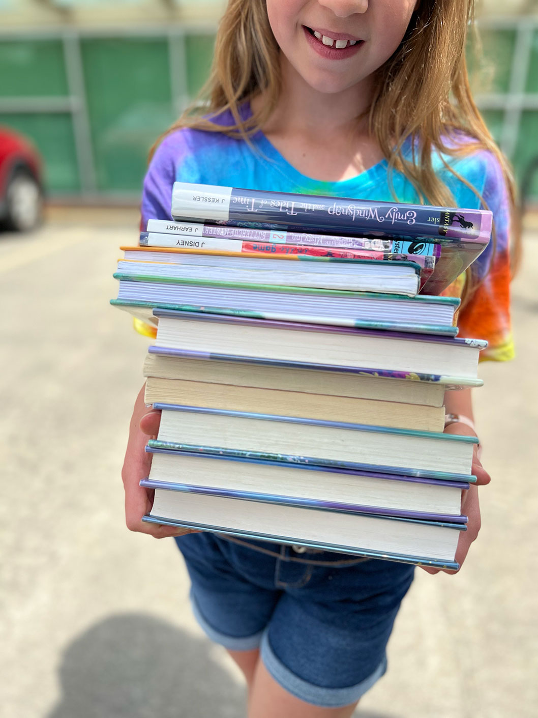 Young girl reading with a stack of books at the library